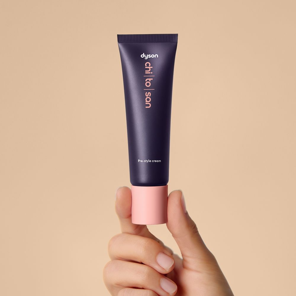 La crema pre-styling Dyson Chitosan da 30 ml tenuta in una mano.