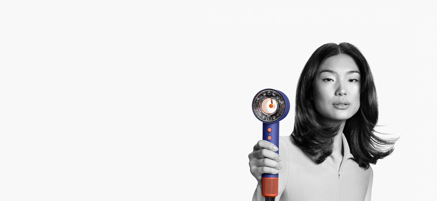 Woman using the Dyson Supersonic Nural hair dryer.